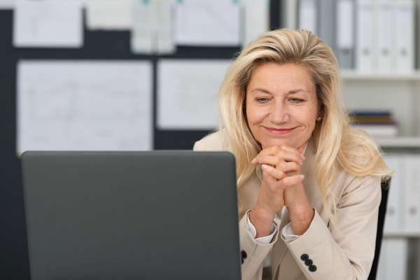 Pleased businesswoman reading her laptop screen