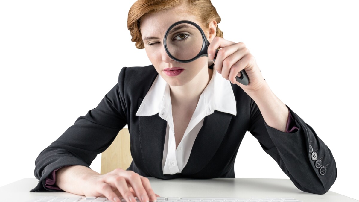 Redhead businesswoman looking through magnifying glass
